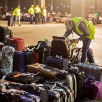 A Brussels airport worker works on a laptop as he stands between luggage that was left behind during the March 22 terrorist attack on Brussels Airport, in a warehouse near the airport on March 24, 2016. The Islamic State group has trained at least 400 fighters to target Europe in deadly waves of attacks, deploying interlocking terror cells like the ones that struck Brussels and Paris with orders to choose the time, place and method for maximum carnage. The FBI is probing the laptops linked to the Brussels attackers. | AP