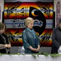 Democratic presidential candidate Hillary Clinton stands for a moment of silence for the victims of the attacks in Brusselswith Puyallup tribal members Rollen Hargrove (left) and Bill Sterud during a roundtable with Washington Tribal Leaders at Chief Leschi School in Puyallup, Washington, Tuesday. | AP