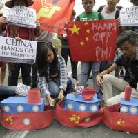 Filipino student activists set fire mock Chinese ships to protest recent island-building and alleged militarization by China off the disputed Spratlys group of islands in the South China Sea during a rally near the Malacanang presidential palace in Manila on March 3. | AP