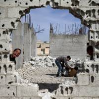 Boys play near the remains of damaged buildings in the rebel-held town of Douma in the eastern Damascus suburb of Ghouta, Syria, on Saturday. | REUTERS