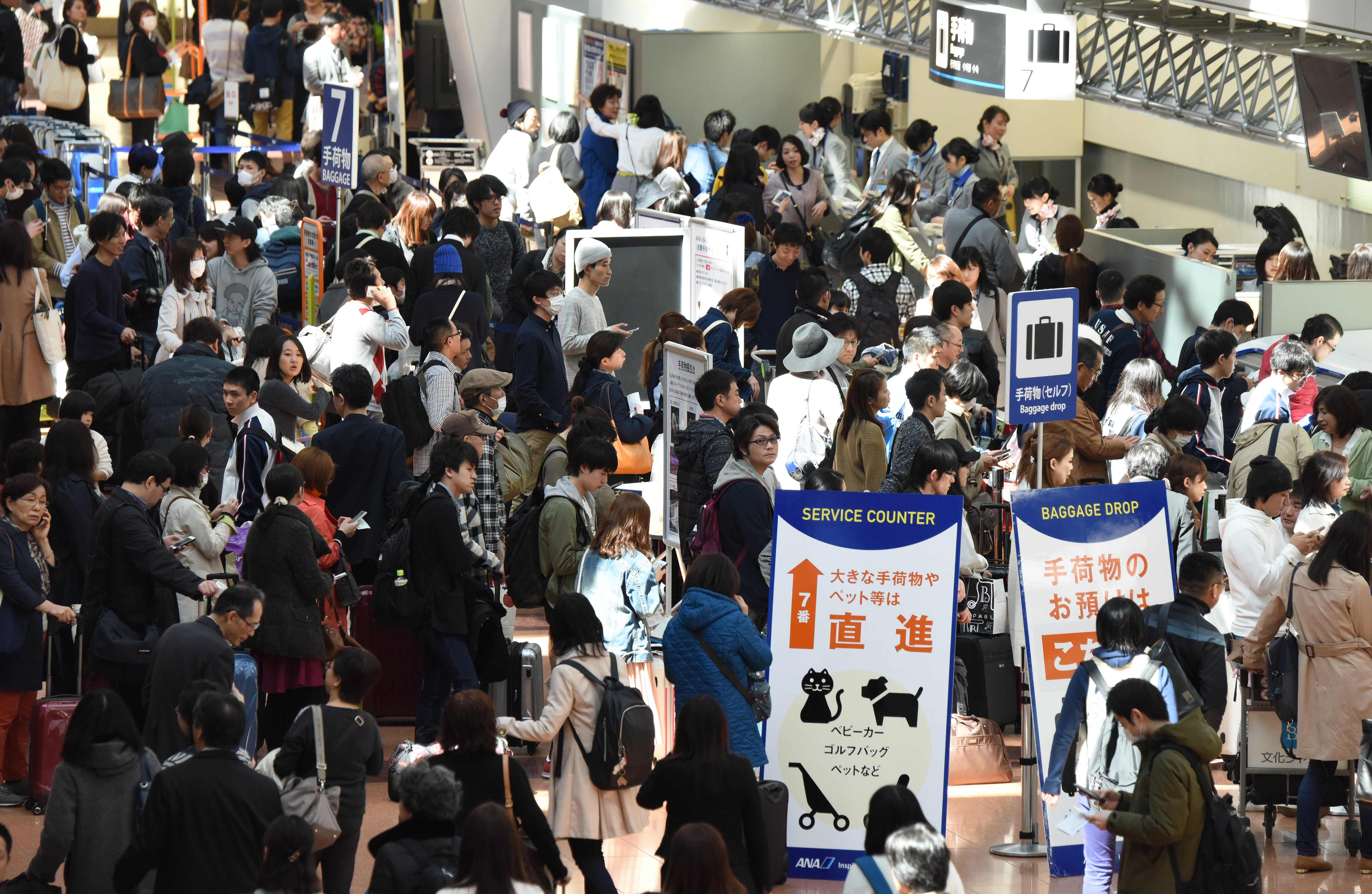 People wait at the ANA counter at Haneda airport on March 22. Staff from Haneda, Narita and Kansai airports said that they already operate at a heightened level of security and therefore do not plan to introduce fresh measures at the moment. | AFP-JIJI