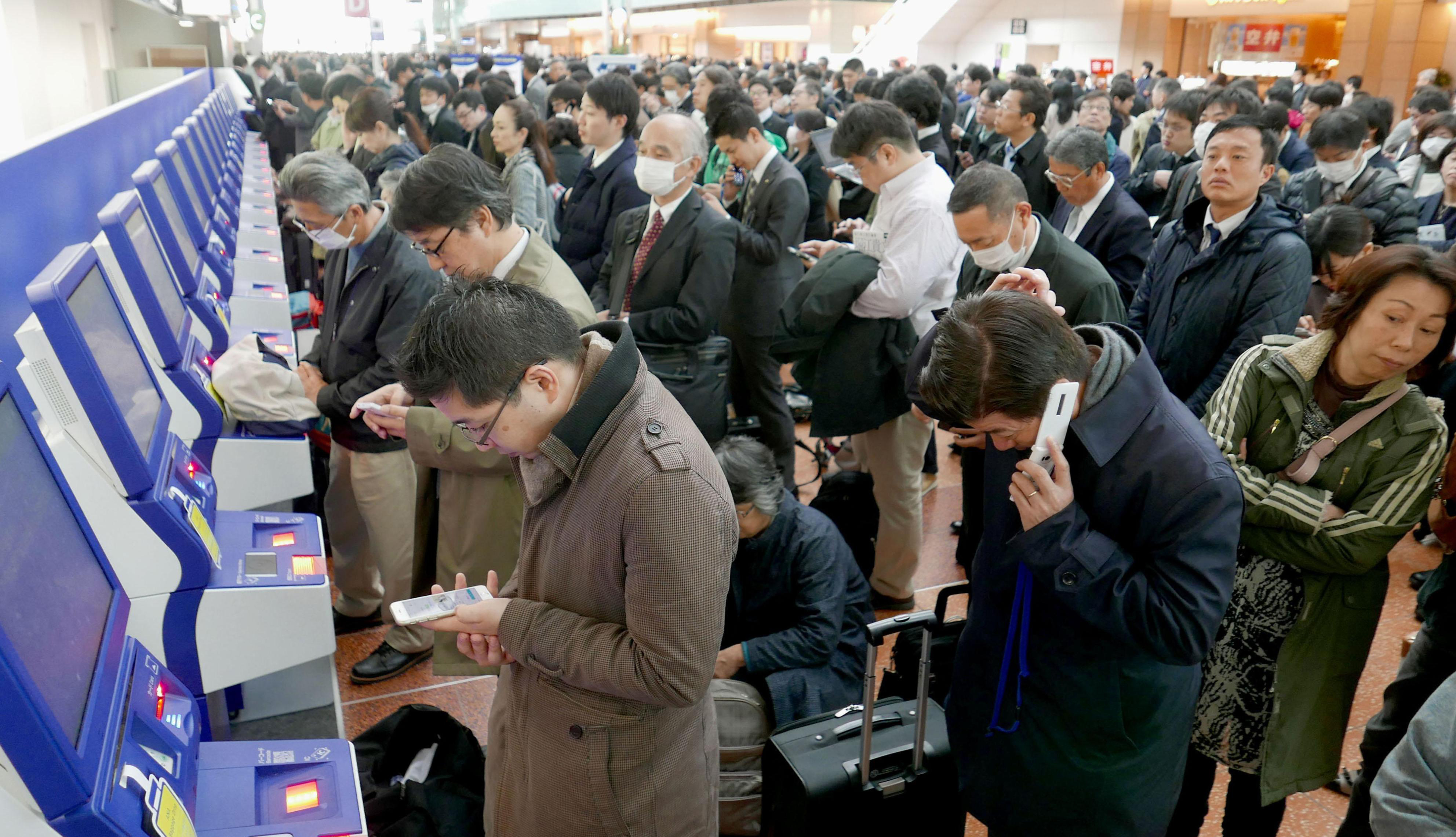 Travelers line up at check-in consoles at Haneda Airport on Tuesday morning after a glitch in ANA's reservation system glitch temporarily grounded dozens of domestic flights. | KYODO