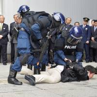 Police subdue suspected suicide bombers Monday during a security drill at Tokyo Station. The exercise was held ahead of the Group of Seven leaders\' summit in May. | KYODO