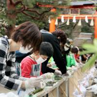Adults and children participate in an event to set a record for the longest line of green tea dumplings in the city of Uji, Kyoto Prefecture, on Sunday. A Guinness World Record\'s official confirmed the line of dumplings, at 341.57 meters, was the world\'s longest. | KYODO