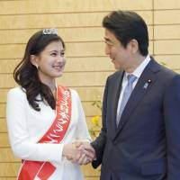 Mika Matsuno, winner of the 2016 Miss Nippon beauty pageant, shakes hands with Prime Minister Shinzo Abe at his office in Tokyo Friday. Matsuno, a 20-year-old sophomore at Keio University, is the daughter of Yorihisa Matsuno, who leads opposition party Ishin no To (Japan Innovation Party). | KYODO