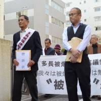 Takeshi Yamauchi (left), leader of a group of 151 plaintiffs seeking to be acknowledged as hibakusha, heads to the Nagasaki District Court on Monday. | KYODO