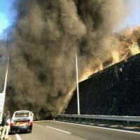 A photo posted to Twitter shows black smoke coming out of the Hachihonmatsu tunnel on the Sanyo Expressway in Higashihiroshima, Hiroshima Prefecture, on Thursday. | KYODO
