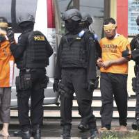 A closer fight: Indonesian police lead away two men who are suspected of involvement in January’s militant attack in Jakarta. The attack has exposed terrorist elements closer to Japan’s shores. Japan's counterterrorism efforts falling short