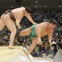 Yokozuna Hakuho shoves Yoshikaze out of the ring on Sunday in Osaka. | KYODO