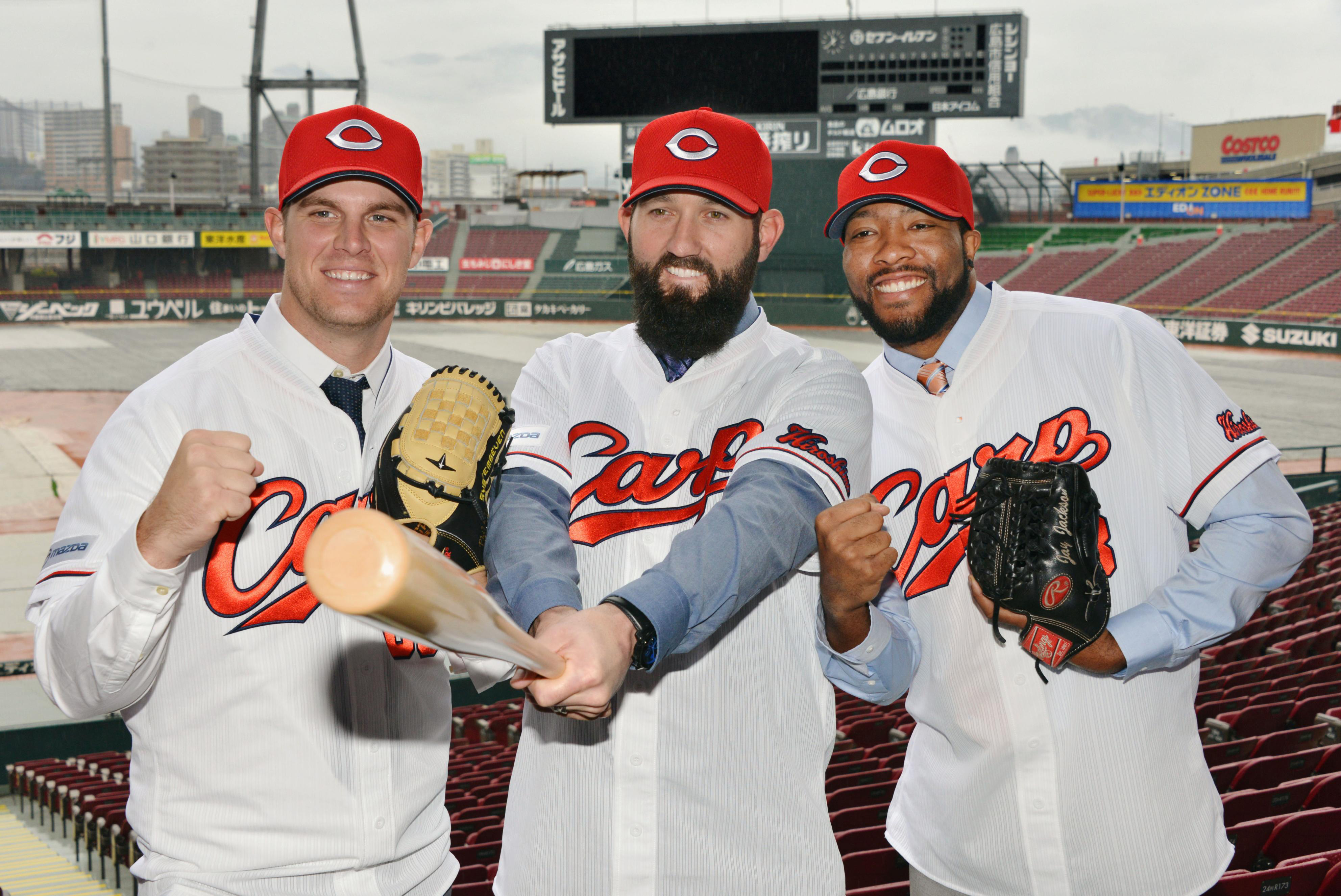 Jason Pridie (center) poses with Carp pitchers Bradin Hagens (left) and Jay Jackson on Jan. 29, at Mazda Stadium. | KYODO