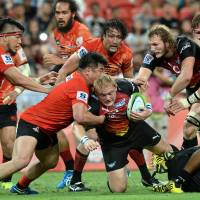 Bulls player Adrian Strauss (center) is tackled by the Sunwolves\' Shota Horie (left) during Saturday\'s Super Rugby match in Singapore. The Bulls defeated the Sunwolves 30-27. | AFP-JIJI