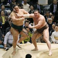 Yokozuna Hakuho shoves Okinoumi during their match at the Spring Grand Sumo Tournament on Tuesday in Osaka. | KYODO