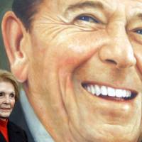 Former U.S. first lady Nancy Reagan stands by an image of a postage stamp of her husband, President Ronald Reagan, in Simi Valley, California, in 2004. Nancy, who was fiercely protective of her husband through a Hollywood career, eight years in the White House, an assassination attempt and her husband\'s Alzheimer\'s disease, died Sunday at 94. | REUTERS