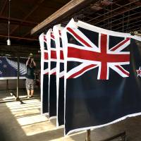 Factory workers hang new designs of the national flag of New Zealand at a factory in Auckland in this file photo. New Zealand voted in favor of retaining the country\'s current flag (foreground) by a margin of 57 percent to 43 percent in a nationwide poll that ended on Thursday. The current flag has been the national symbol since 1902. | REUTERS
