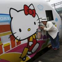 Fans pose next to the Hello Kitty-themed Taroko Express train in Taipei on Monday. The train made its inaugural round-trip journey from Taipei to Taitung the same day, according to the Taiwan Railways Administration. | REUTERS