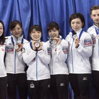 Japan women\'s curling team members, including coach J.D. Lind (far right), hold their silver medals after losing to Switzerland in the final of the World Women\'s Curling Championship on Sunday. | KYODO
