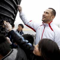 Koji Murofushi, the sports director of the Tokyo 2020 Organising Committee, and children polish the 1964 Olympic cauldron at the Ishinomaki General Sports Park, Miyagi Prefecture, on March 6. | TOKYO 2020 &#8212; SHUGO TAKEMI