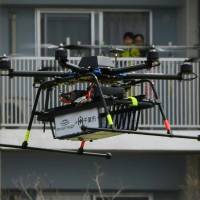 A drone developed by the Autonomous Control Systems Laboratory (ACSL) flies beside a condominium during a field test in Chiba Prefecture on Monday. | AFP-JIJI
