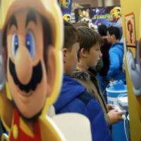 Young visitors to the Legends of Gaming Live event in London play \"Super Mario Maker,\" a game developed by Nintendo for the Wii U, in this photo from September. | BLOOMBERG