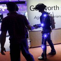 Ugo Dumont, a volunteer for the Genworth R70i Aging Experience, walks in the R70i Age Suit during a demonstration at the Liberty Science Center in Jersey City, New Jersey, Tuesday. Exoskeleton suit mimics life's creaks, weaknesses at 85 to boost awareness