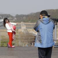 Visitors take souvenir pictures Friday at the Imjingak Pavilion in Paju, South Korea. The pavilion stands near the border with North Korea, which can be seen behind them. | AP