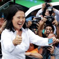 Peru presidential candidate Keiko Fujimori waves to supporters and press after voting in the presidential election in Lima Sunday. | REUTERS