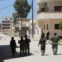 Members of the Kurdish internal security forces (known as the Asayish) patrol the streets in the northeastern Syrian city of Qamishli on Saturday. Kurdish fighters and Syrian government representatives agreed to an indefinite cease-fire after three days of clashes in the northeastern city of Qamishli, Kurdish security forces said. | AFP-JIJI