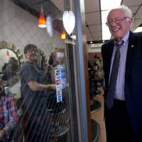 Democratic presidential candidate Bernie Sanders greets customers and workers at a hair salon while going for a walk in the Jackson Heights neighborhood of the Queens borough of New York Monday. | AP
