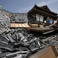 Police rescue team members check for the possibility of people trapped in collapsed houses in Mashiki, Kumamoto Prefecture on Friday, after an unusually strong overnight earthquake. | AP