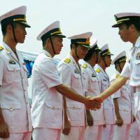 Maritime Self-Defense Force Capt. Haruhiko Morishita (right), the commander of the 15th Escort Division, greets Vietnamese Navy officers during a welcoming ceremony for two Japanese guided-missile destroyers at Cam Ranh Bay in Vietnam on Tuesday. | AFP-JIJI