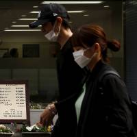 People walk past a barbershop in Tokyo last week. | REUTERS