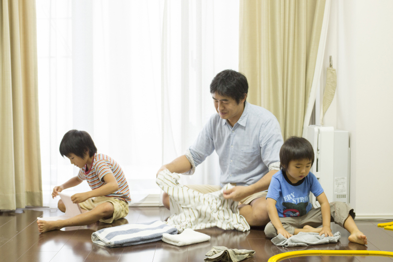 At-home-dad Taizo Horikomi folds laundry together with his sons in October. | COURTESY OF TAIZO HORIKOMI