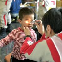 A boy receives care from a doctor at a temporary shelter set up at a gym in Mashiki, Kumamoto Prefecture, on Sunday. | AP