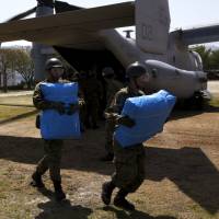 Self-Defense Force personnel unload relief supplies from a U.S. MV-22 Osprey in the village of Minamiaso, Kumamoto Prefecture, on Friday. | REUTERS