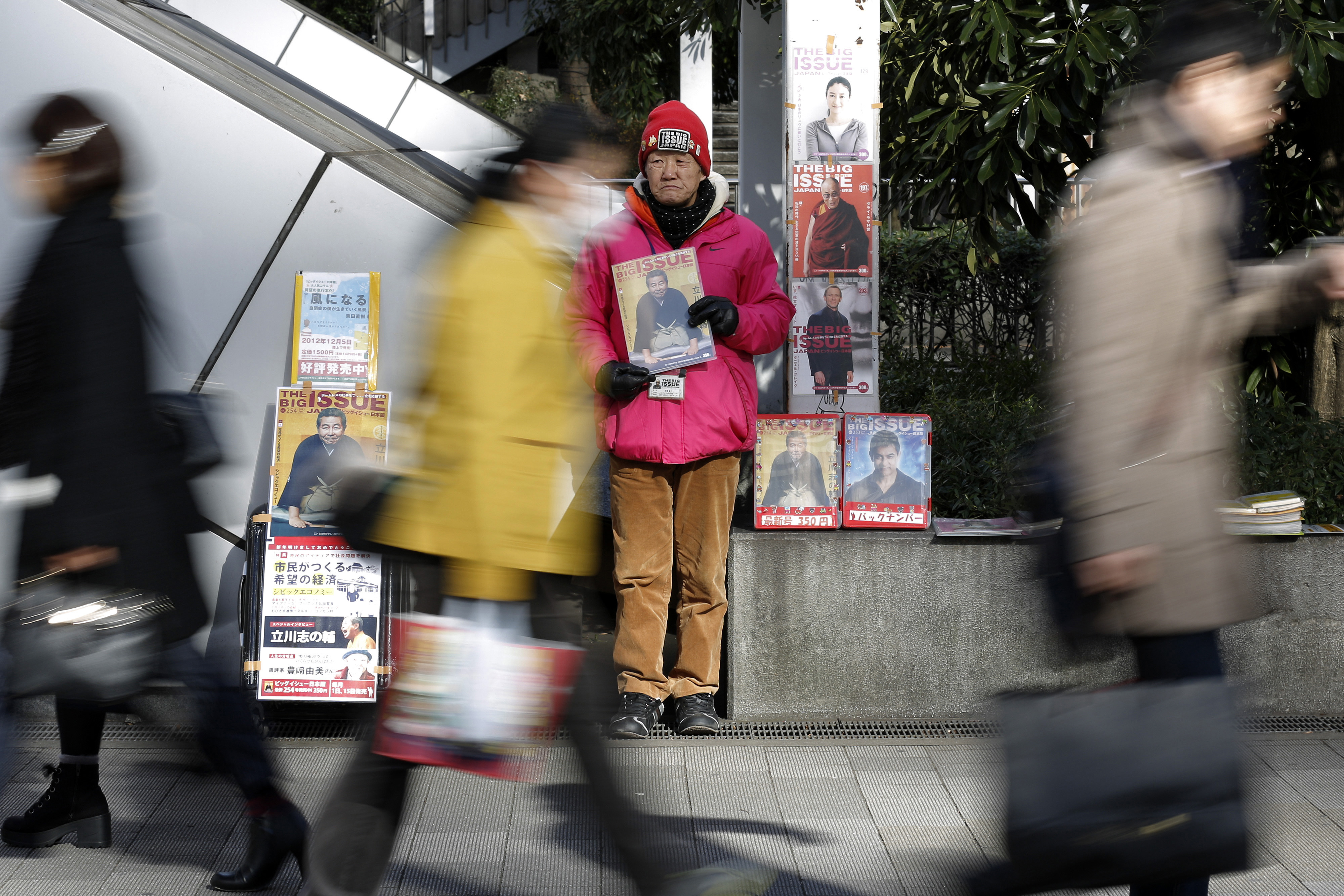 Homeless Toyoji Yoshizawa sells copies of the Big Issue Japan magazine on a Tokyo street in January 2015. Experts say income disparity has widened under Prime Minister Shinzo Abe, leaving a larger portion of the population, especially the young, below the poverty line. | BLOOMBERG