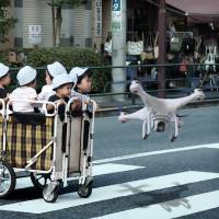 An artist’s rendering shows a sentinel drone guiding a cart of nursery school children. Officials say the drones, part of the ambitious Roho Care project, will be ready for a trial run as early as summer 2016. Robotics makes baby steps toward solving Japan's child care shortage