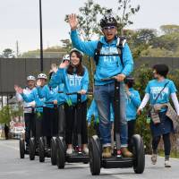 People ride Segways during a demonstration tour in Futako-Tamagawa, in Tokyo’s Setagaya Ward, on Tuesday. The popular vehicles were all but banned on public roads until restrictions were eased last year. A regular driver’s license is needed to drive them, and tour organizers hope to open services to the public in summer. | SATOKO KAWASAKI