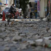 A cyclist passes by the debris at an arcade street in Kumamoto city on April 17, 2016. | AP