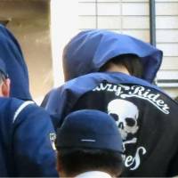 A man in his 30s (right) who was arrested for allegedly stabbing his family members enters a police station in Hamamatsu, Shizuoka Prefecture, Friday morning. | KYODO
