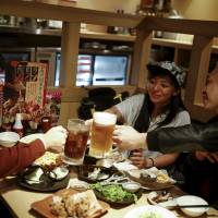 Professional wrestler Kris Wolf (center) raises a toast with fans Eiichi Nakazato (right) and Eishi Matsumoto at a Tokyo restaurant on March 12. | REUTERS