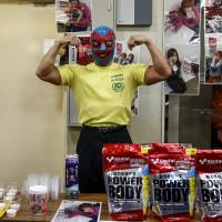 A man strikes a pose as he sells high protein foods outside a Stardom wrestling show in Tokyo on Dec. 23, 2015. | REUTERS