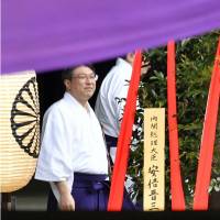 A masakaki wooden tribute signed by Prime Minister Shinzo Abe (left) is offered to Yasukuni Shrine on Thursday. | KYODO