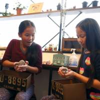 Anna (center), 11, and Yuna Cheung (right), 11, from Great Britain hold hedgehogs as their mother watches. | REUTERS