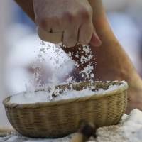A sumo wrestler grabs a handfull of salt before competing in a Honzumo bout on Monday at Yasukuni Shrine. | REUTERS
