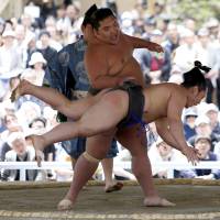 A sumo wrestler sends this opponent flying during a Honozumo bout at Yasukuni Shrine on Monday. | REUTERS