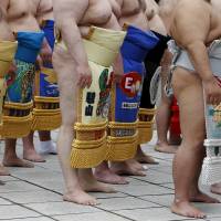 Sumo wrestlers wearing colorful and ornate kesho-mawashi, which often bare the names of corporate sponsors, assemble to pray before the start of the  Honozumo. | REUTERS