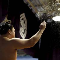 Mongolia-born grand sumo champion Hakuho throws salt, which is believed to purify the ring before a bout. | REUTERS