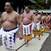 After prayer, yokozuna wearing tsuna — thick rope decorated with paper that alludes to lightning — exit the shrine and head for the ring. | REUTERS