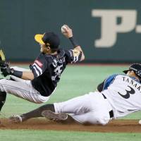 The Fighters\' Kensuke Tanaka slides into Hawks infielder Keizo Kawashima during their game on Sunday Tokyo Dome. | KYODO