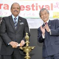 Indian Ambassador Sujan R. Chinoy (left) lights a traditional oil lamp during the opening ceremony of the Sakura Festival 2016, as President of the Japan-India Association Hiroshi Hirabayashi (right) applauds at the embassy in Tokyo on March 25. The sakura festival at the embassy showcases Indian cultural performances, food and handicrafts. | YOSHIAKI MIURA